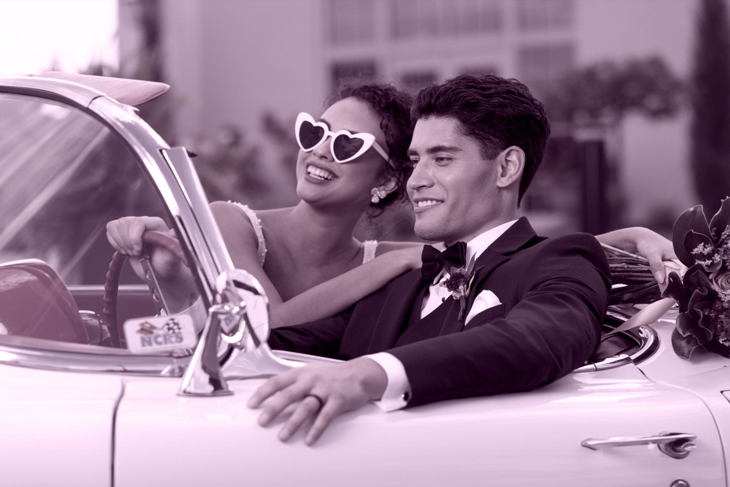 Bride and Groom driving in a older car highlighting their sense of style and how are looks appear in real situations.